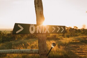 A directional signpost with arrows pointing to the right, mounted on a wooden post with a wire fence in the foreground. - CASA ÔNIX (Alto Paraíso de Goiás)
