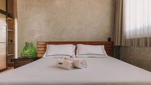 A neatly made bed with white linens and pillows, a wooden headboard, and a green decorative object on a nightstand. - CASA ÔNIX (Alto Paraíso de Goiás)