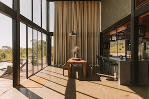 A modern kitchen with a bar area, large windows, and a view of the outdoors. - CASA ÔNIX (Alto Paraíso de Goiás)