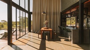 A modern kitchen with a bar area, large windows, and a view of the outdoors. - CASA ÔNIX (Alto Paraíso de Goiás)