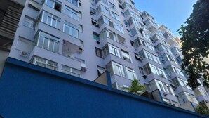 A multi-story residential building with balconies, air conditioning units, and a blue facade.