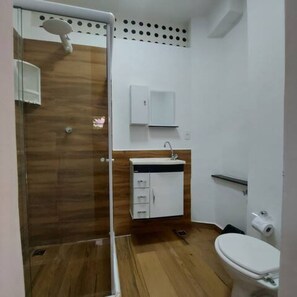 A bathroom with a shower, toilet, sink, and cabinet.