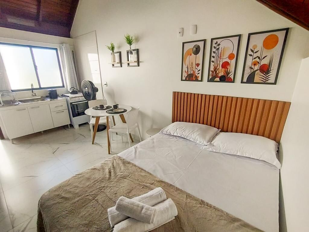 Habitación de hotel con cama, escritorio, silla y una pequeña kitchenette.
