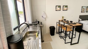 A compact hotel room with a kitchenette, a small dining area, and a bed.