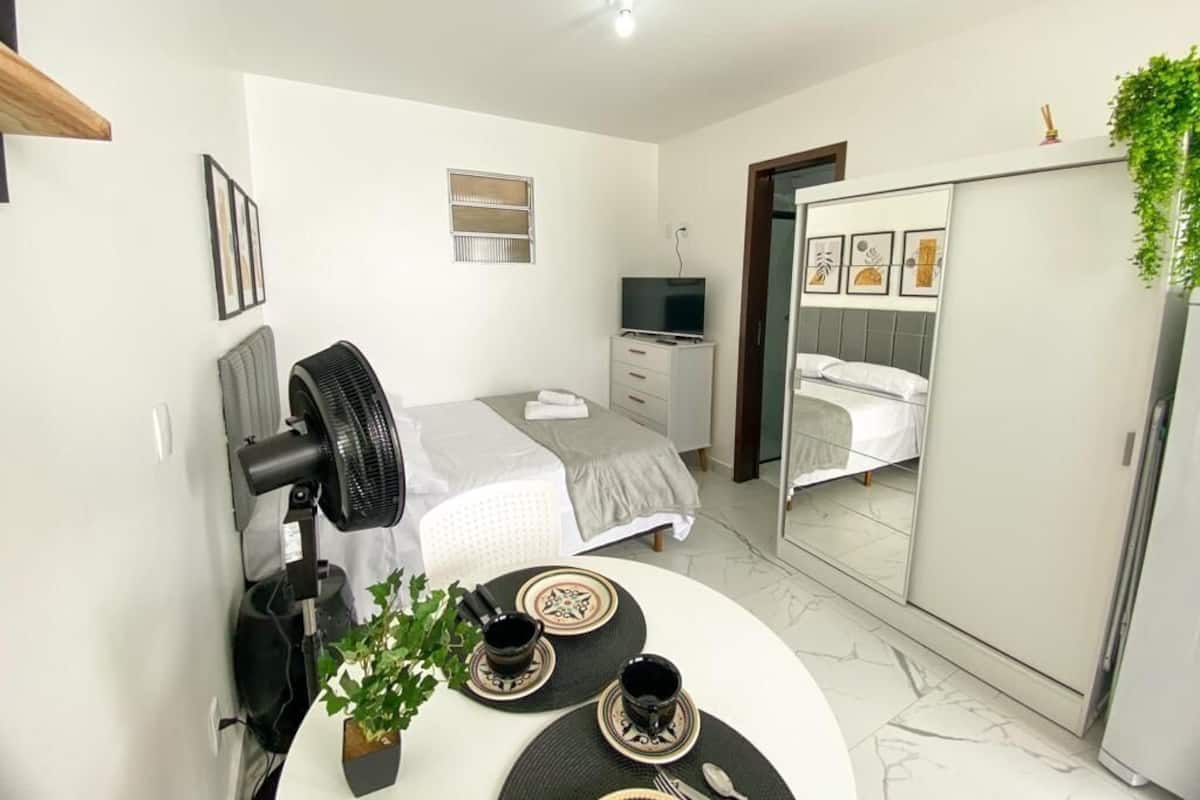 Ein modernes Schlafzimmer mit Bett, Nachttisch, Fernseher, Kleiderschrank und Spiegel.