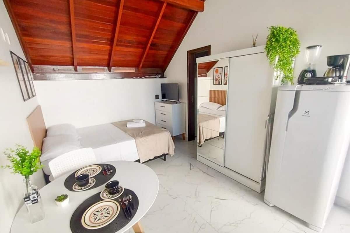 Ein gemütliches Schlafzimmer mit Bett, Nachttisch und Spiegel. Ein Essbereich mit Tisch und Stühlen ist ebenfalls zu sehen.
