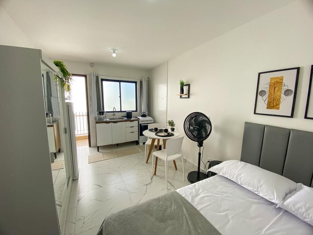 Une chambre d’hôtel moderne équipée d’un lit, d’un bureau, d’une chaise et d’un ventilateur.