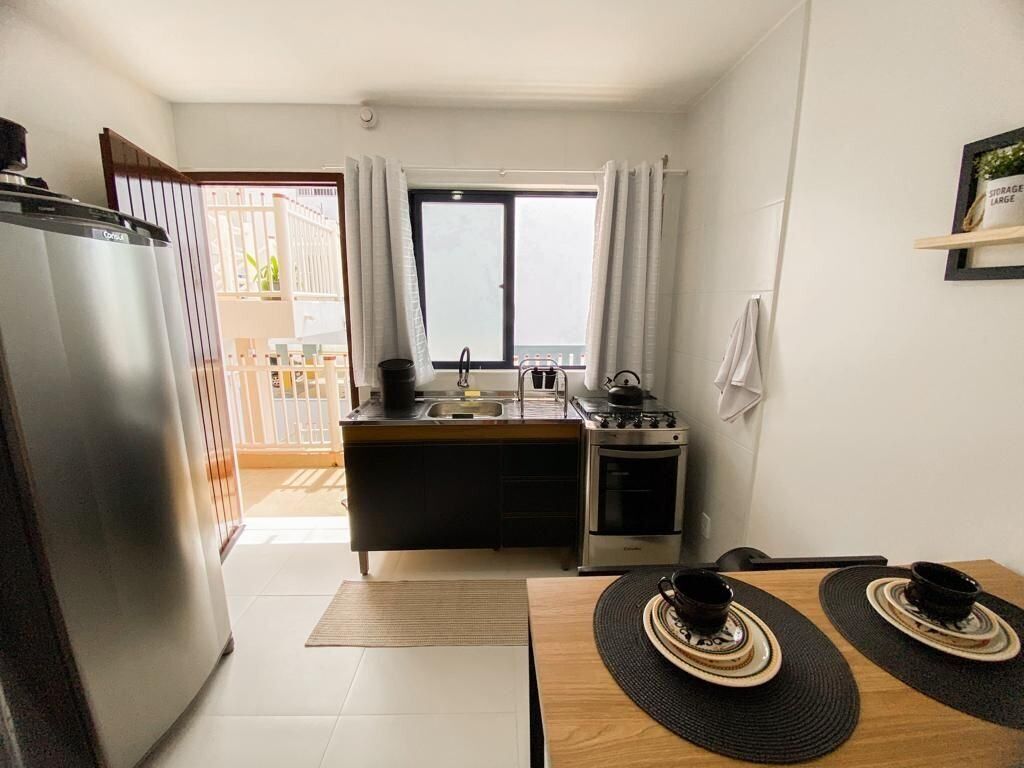 Eine kleine Küche mit Kühlschrank, Herd und Spüle. Es gibt einen Essbereich mit Tisch und Stühlen.