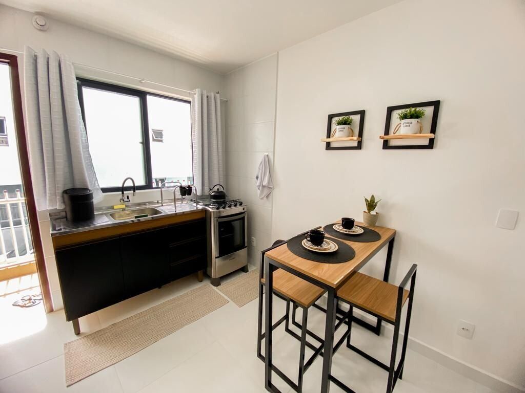 Cocina compacta con comedor, que incluye estufa, pileta y una pequeña mesa con sillas.