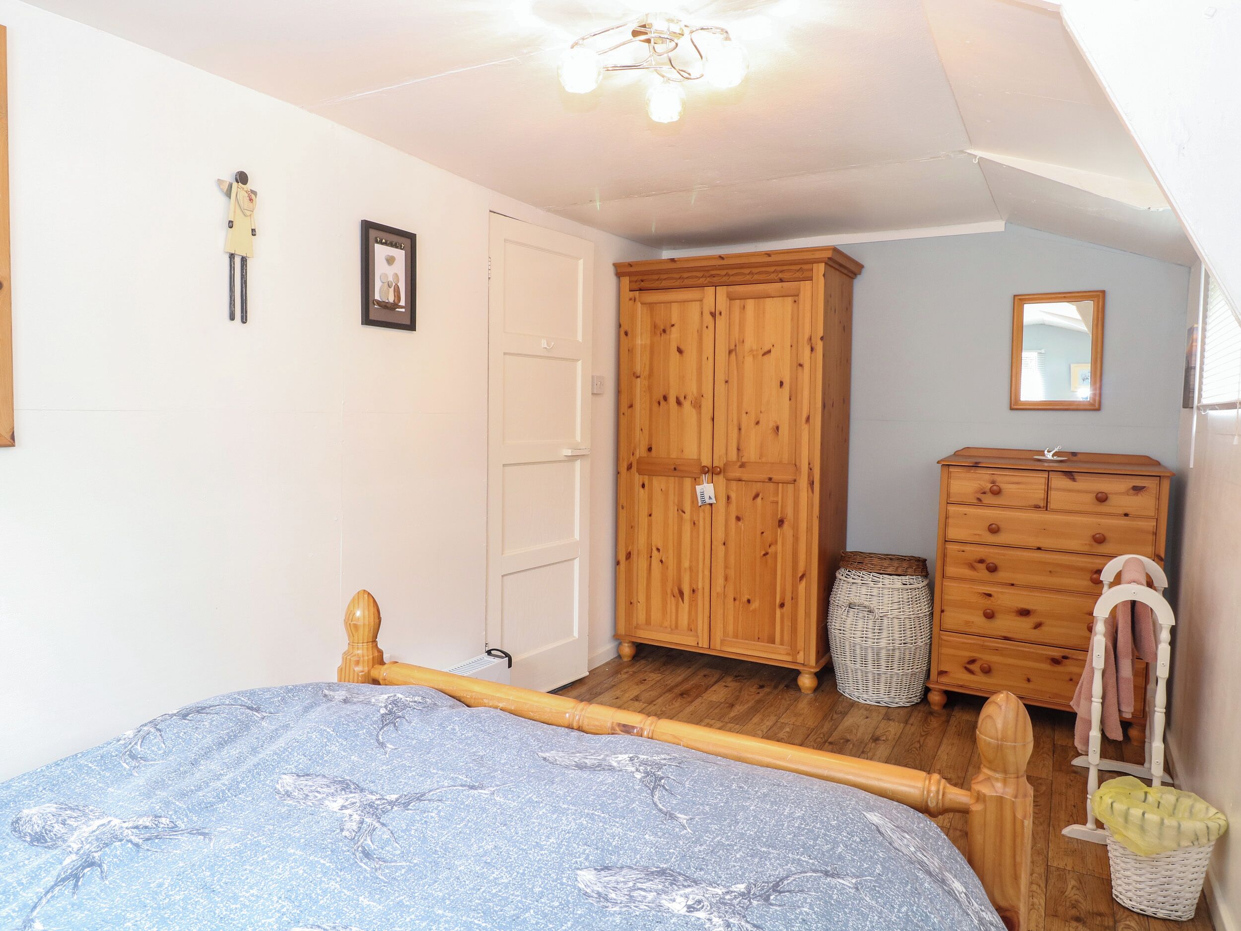 A bedroom with a wooden bed, a wardrobe, a dresser, and a mirror.