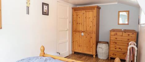 A bedroom with a wooden bed, a wardrobe, a dresser, and a mirror.