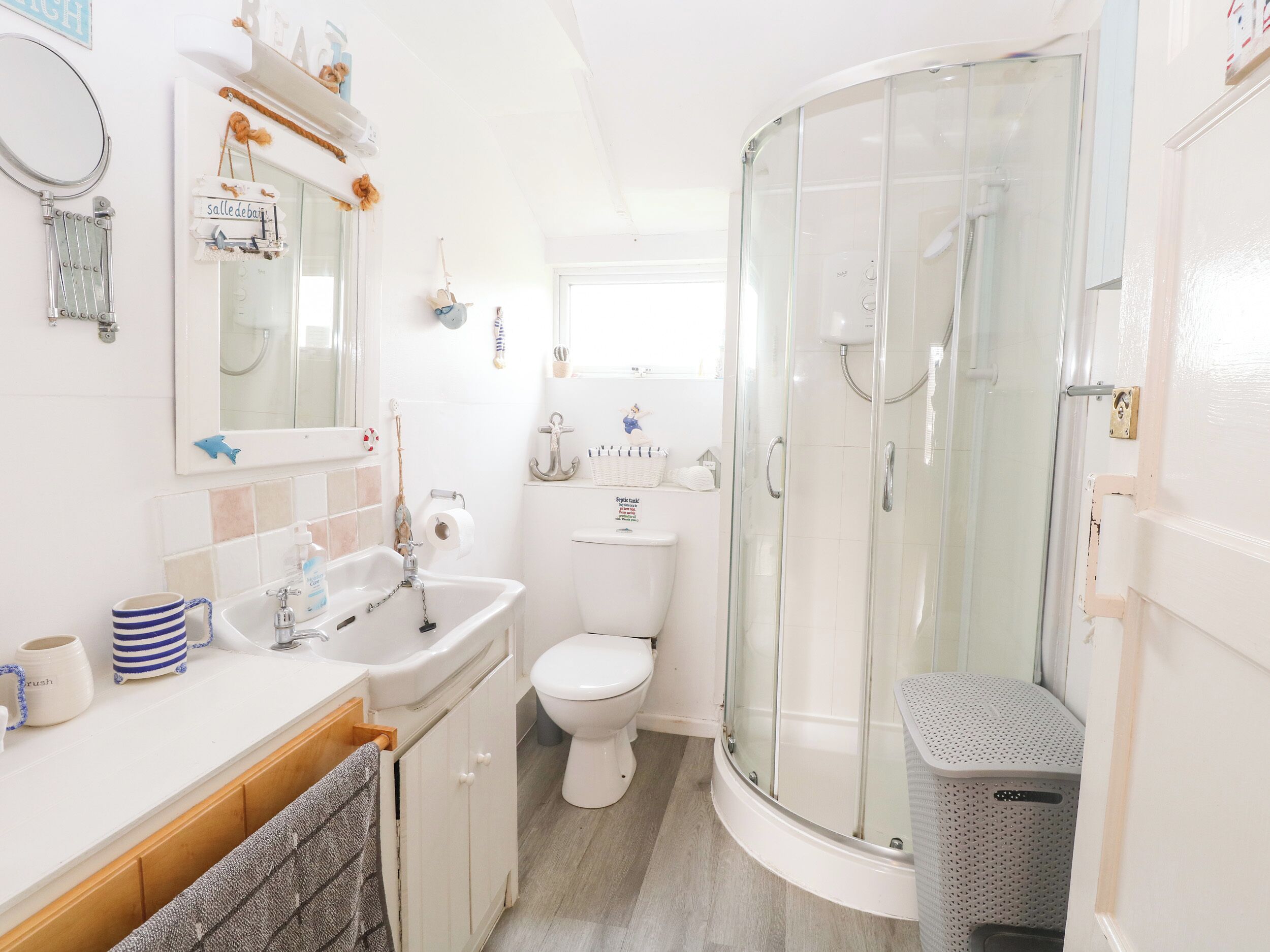 Un bagno con doccia, wc, lavandino e un piccolo cestino.