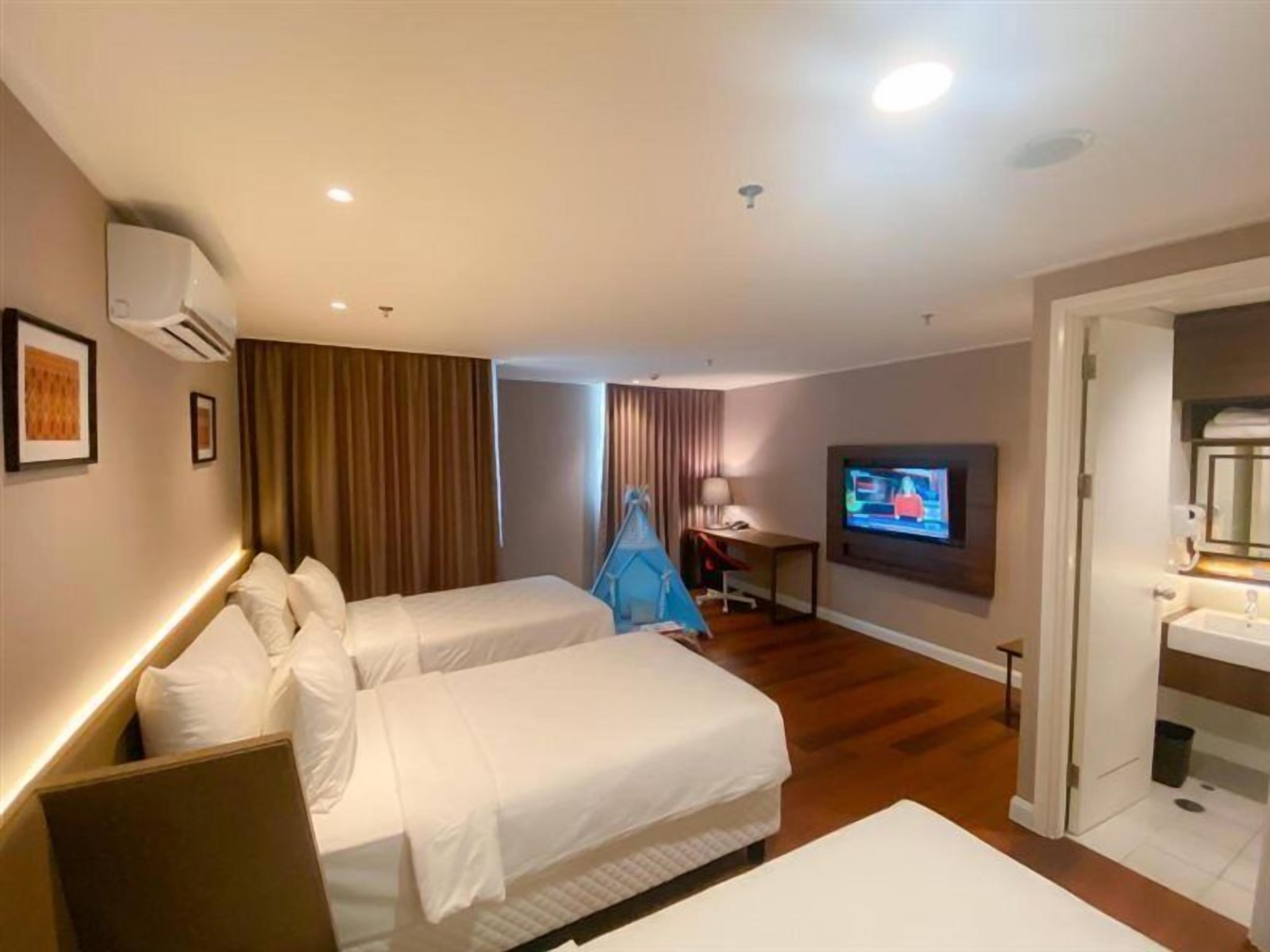 Una habitación de hotel con dos camas, un escritorio, televisión y baño.