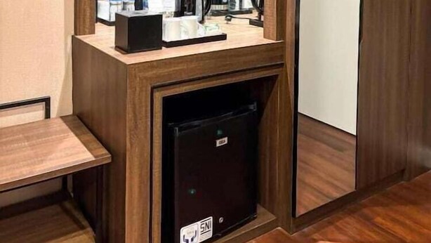 Une chambre d’hôtel équipée d’un bureau en bois, d’un miroir, d’un mini-réfrigérateur et d’un coin café.