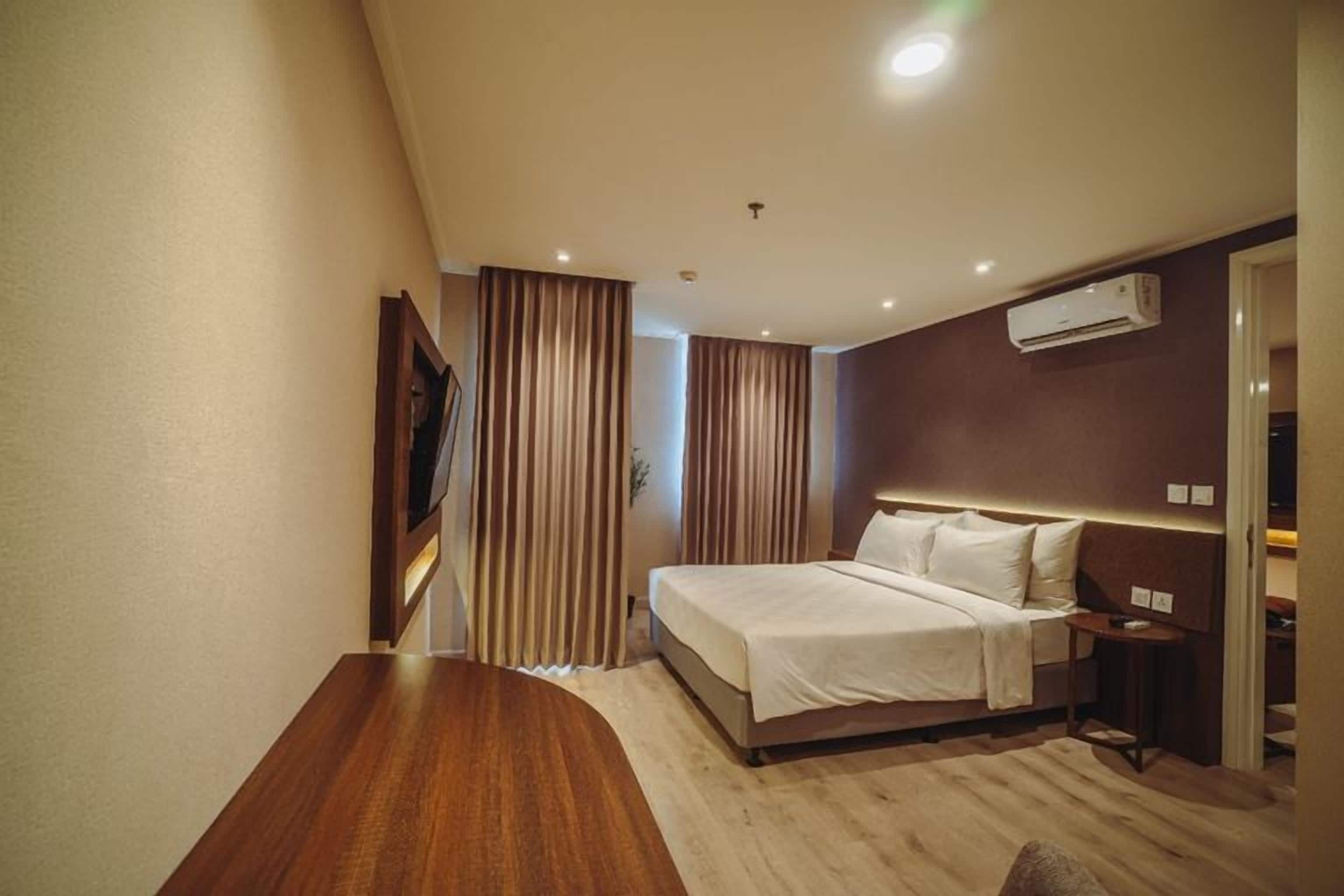 Une chambre d’hôtel équipée d’un lit, d’un bureau, d’une télévision et d’un appareil de climatisation.