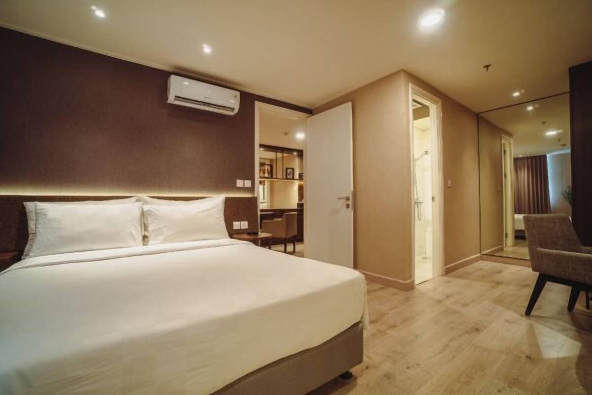 Una habitación de hotel con una cama grande, un equipo de aire acondicionado, un escritorio y una silla.