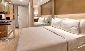 A hotel room with a large bed, a bedside table, and a mirror. - Swiss-Belcourt Serpong (SOUTH TANGERANG)