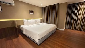 Une chambre d’hôtel avec un lit, un plancher en bois, un climatiseur fixé au mur et un rideau.
