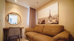 Une pièce avec un canapé marron, un miroir rond, une petite table et un grand tableau représentant un paysage urbain accroché au mur.
