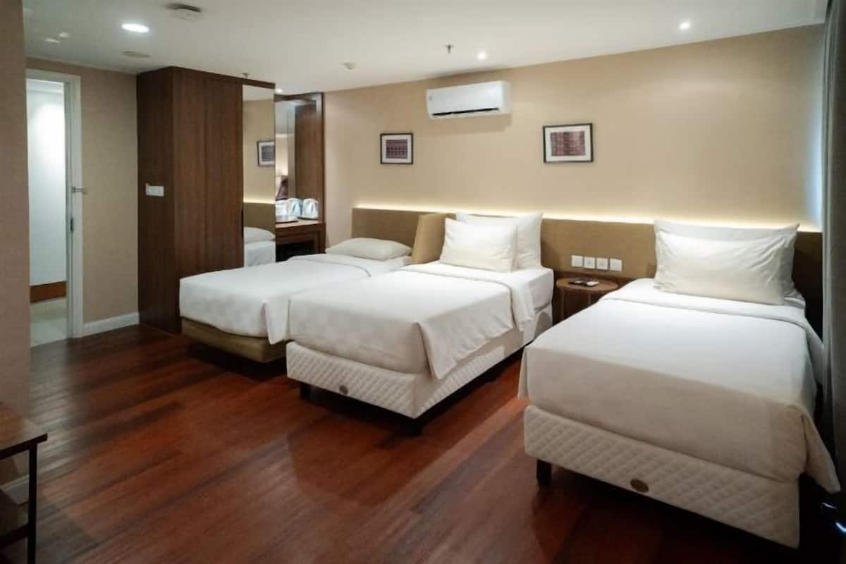 Habitación de hotel con dos camas, piso de madera, un espejo y un aire acondicionado.