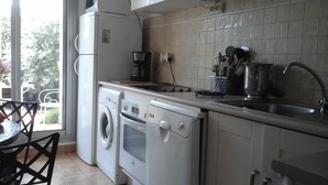 Une cuisine compacte équipée d’un lave-linge, d’une machine à café et d’un évier.