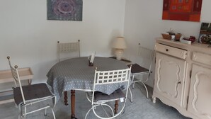 Un coin repas comprenant une table ronde, deux chaises, une lampe, un meuble et des œuvres d’art murales.