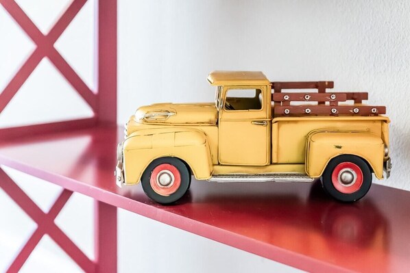 A yellow toy truck with a brown bed on a red shelf.