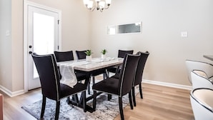 A dining area with a table, chairs, a chandelier, and a mirror on the wall. - Bayou Bengal Royal Stay-n-Tailgate by LSU - BC1025 (Baton Rouge)