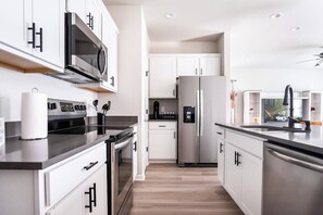Une cuisine moderne dotée d’appareils électroménagers en acier inoxydable, de meubles blancs et d’un îlot central.