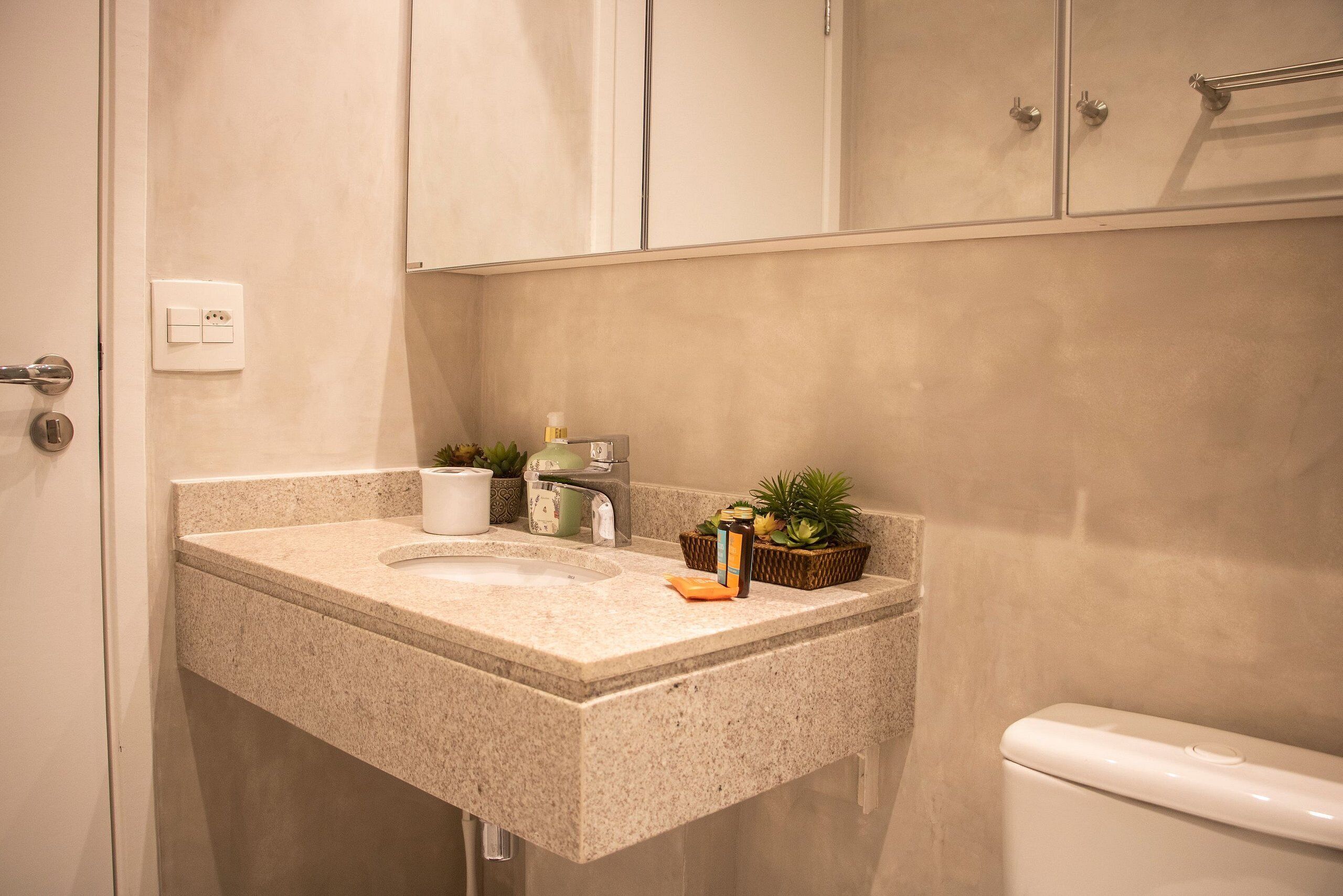 A bathroom with a granite countertop, a toilet, and cabinets.
