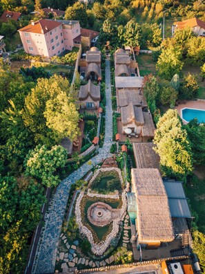 An aerial view of a residential area with multiple houses, a central circular garden, and a swimming pool. - Feronia Suites (Kartepe)