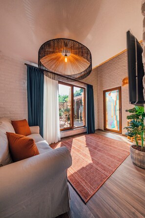 A modern living room with a sofa, a patterned rug, and a large window with curtains. - Feronia Suites (Kartepe)
