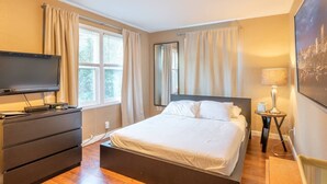 A hotel room with a bed, a TV, a dresser, a lamp, and a painting on the wall. - Studio, perfect for students on rotation at Oregon Health & Sciences University. (Portland)