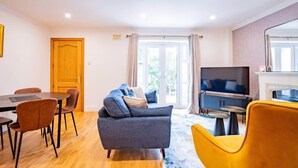 Una sala de estar moderna con un sofá, sillas, un televisor y una chimenea.