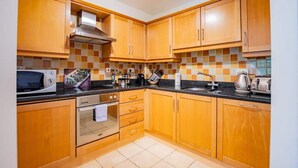 Una cocina con armarios de madera, microondas, horno y salpicadero de azulejos.