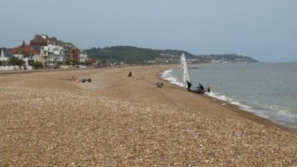 A pebbled beach with a sailboat, buildings in the background, and a clear sky. - 2 bedroomed cottage in Hythe, Kent, close to amenities and beach. Dogs welcome. (Hythe)