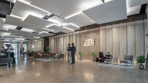 A modern lobby with a wooden reception desk, seating areas, and a spacious layout.