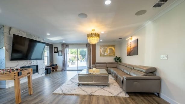 A spacious living room with a large flat-screen TV, a fireplace, a sofa, and a coffee table.