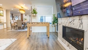 A modern living room with a wooden coffee table, a fireplace, and a dining area with chairs and a table.