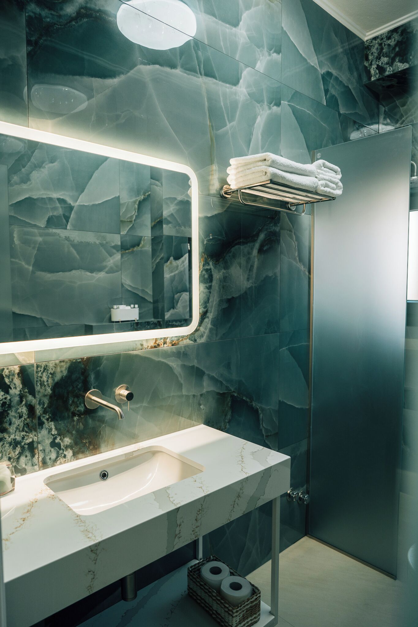 A bathroom with a marble sink, a large mirror, and a towel rack.