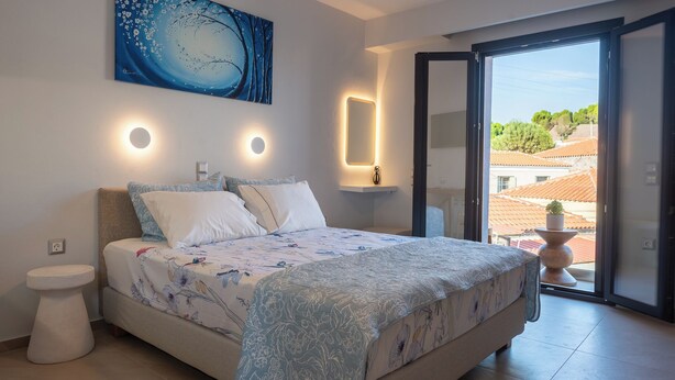 A bedroom with a bed, bedside table, and a view of the outside.