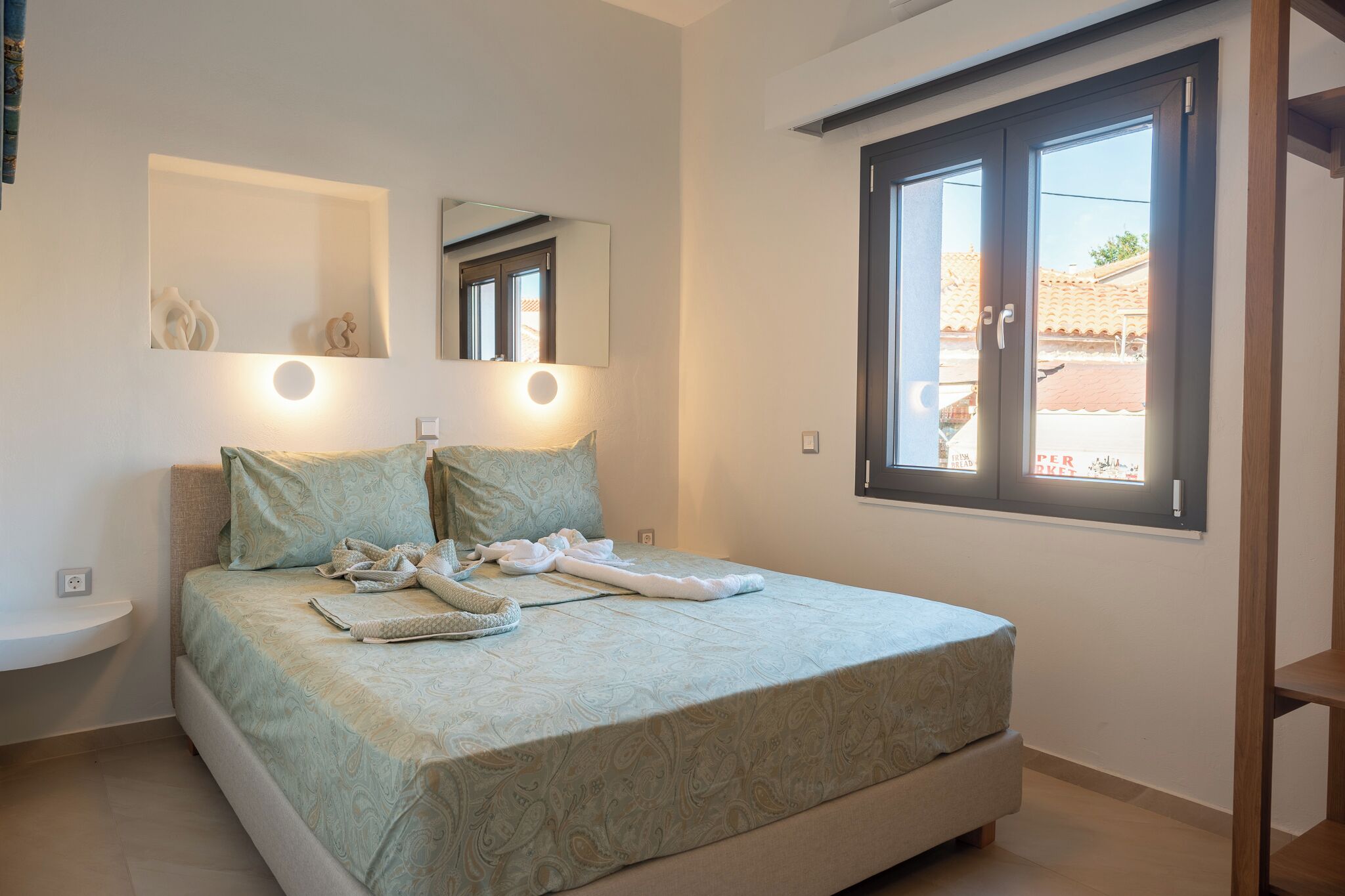 Une chambre à coucher avec un lit, une table de chevet et une fenêtre donnant sur l’extérieur.
