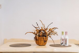 Una cesta de mimbre llena de plantas secas sobre una mesa con dos botellas de agua.