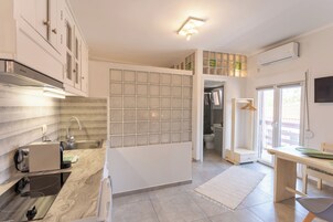 Una cocina moderna con estufa integrada, un lavamanos y una encimera con cafetera. Se ve una ventana con vistas al exterior.