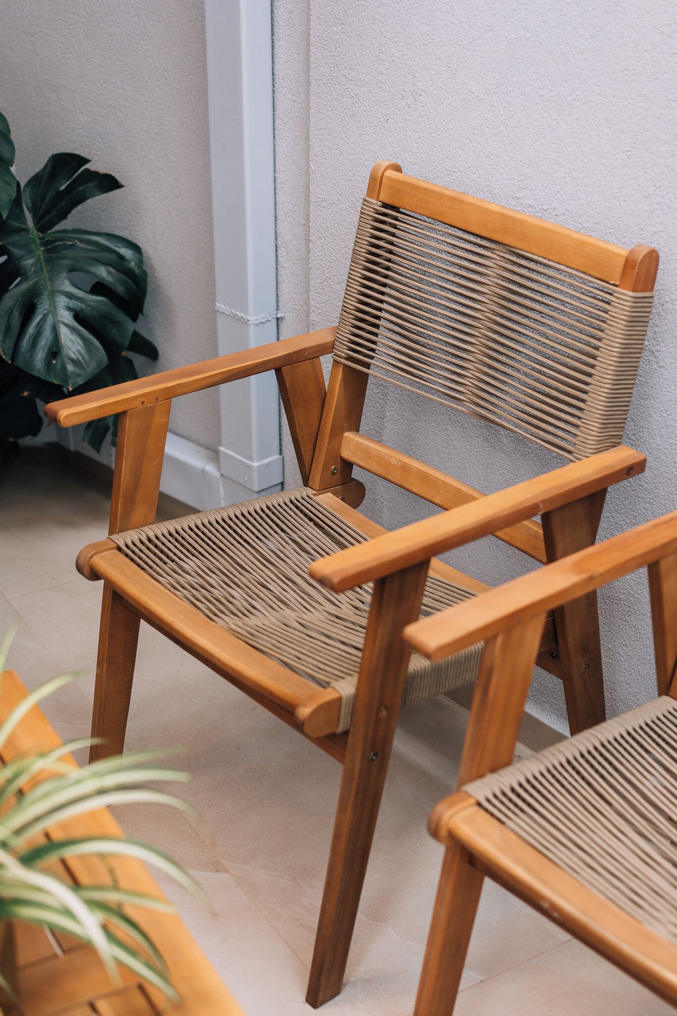 Une chaise en bois avec un dossier et des accoudoirs en osier, posée sur un sol carrelé.