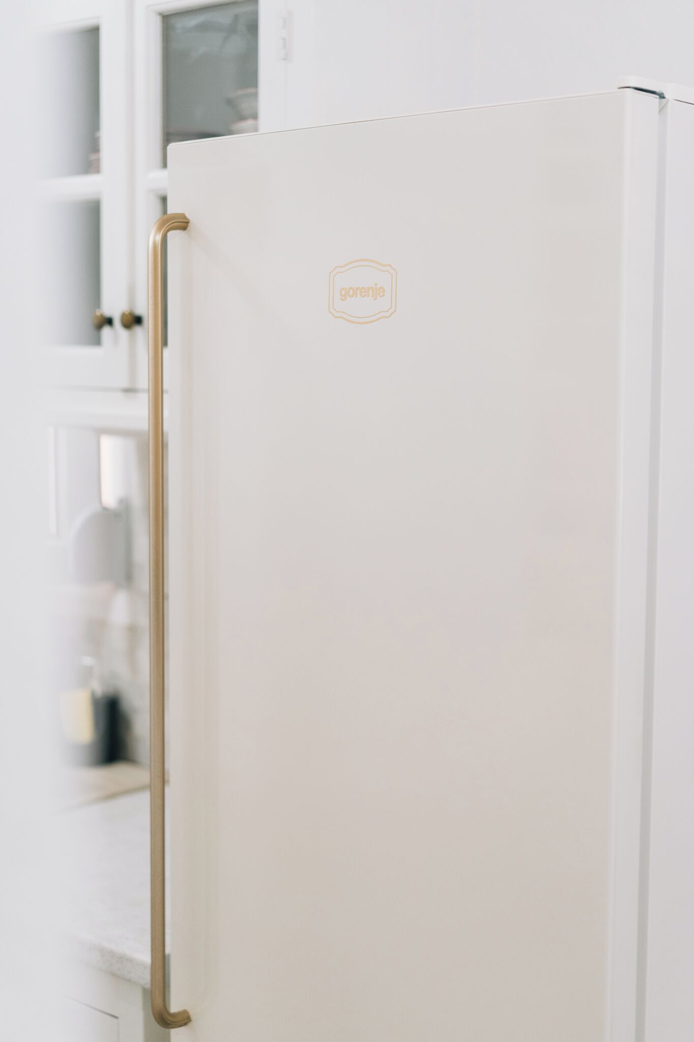 Un réfrigérateur blanc avec une poignée dorée et un logo sur la porte.