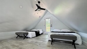 Un dormitorio con dos camas, un ventilador de techo y una puerta que da a un balcón.