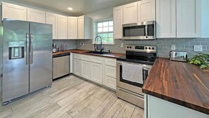 Una cocina moderna con armarios blancos, electrodomésticos de acero inoxidable y encimera de madera.