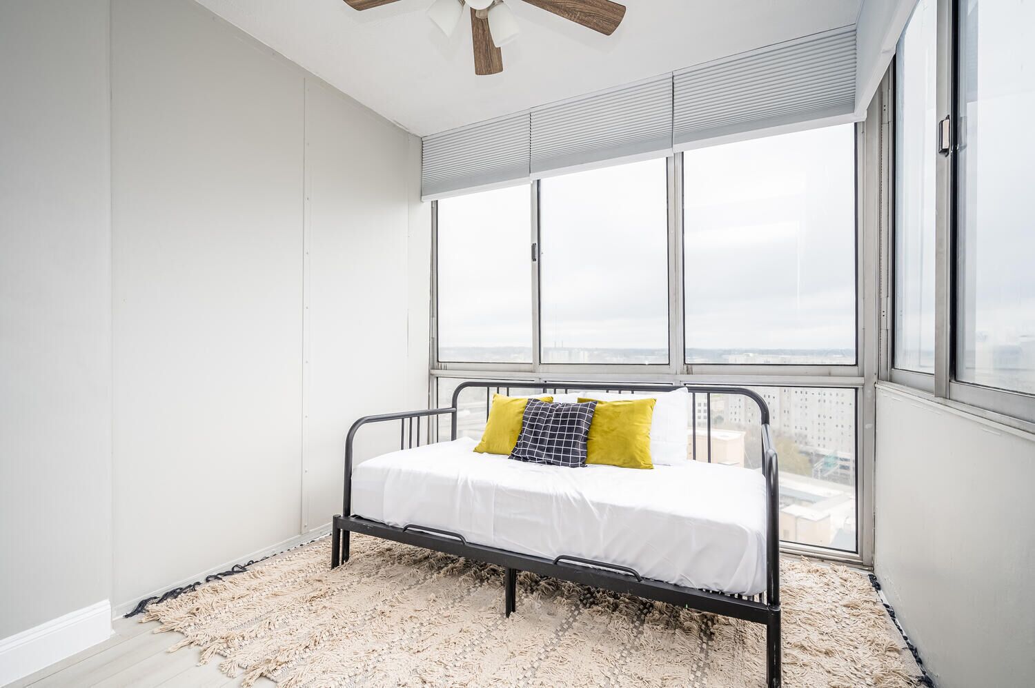 Ein Schlafzimmer mit einem Bett, einem großen Fenster und einem Deckenventilator.