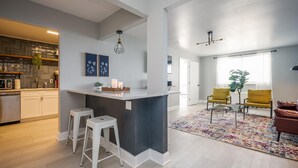 Une cuisine moderne dotée d’un îlot central, de tabourets de bar et d’un coin repas avec des chaises jaunes.